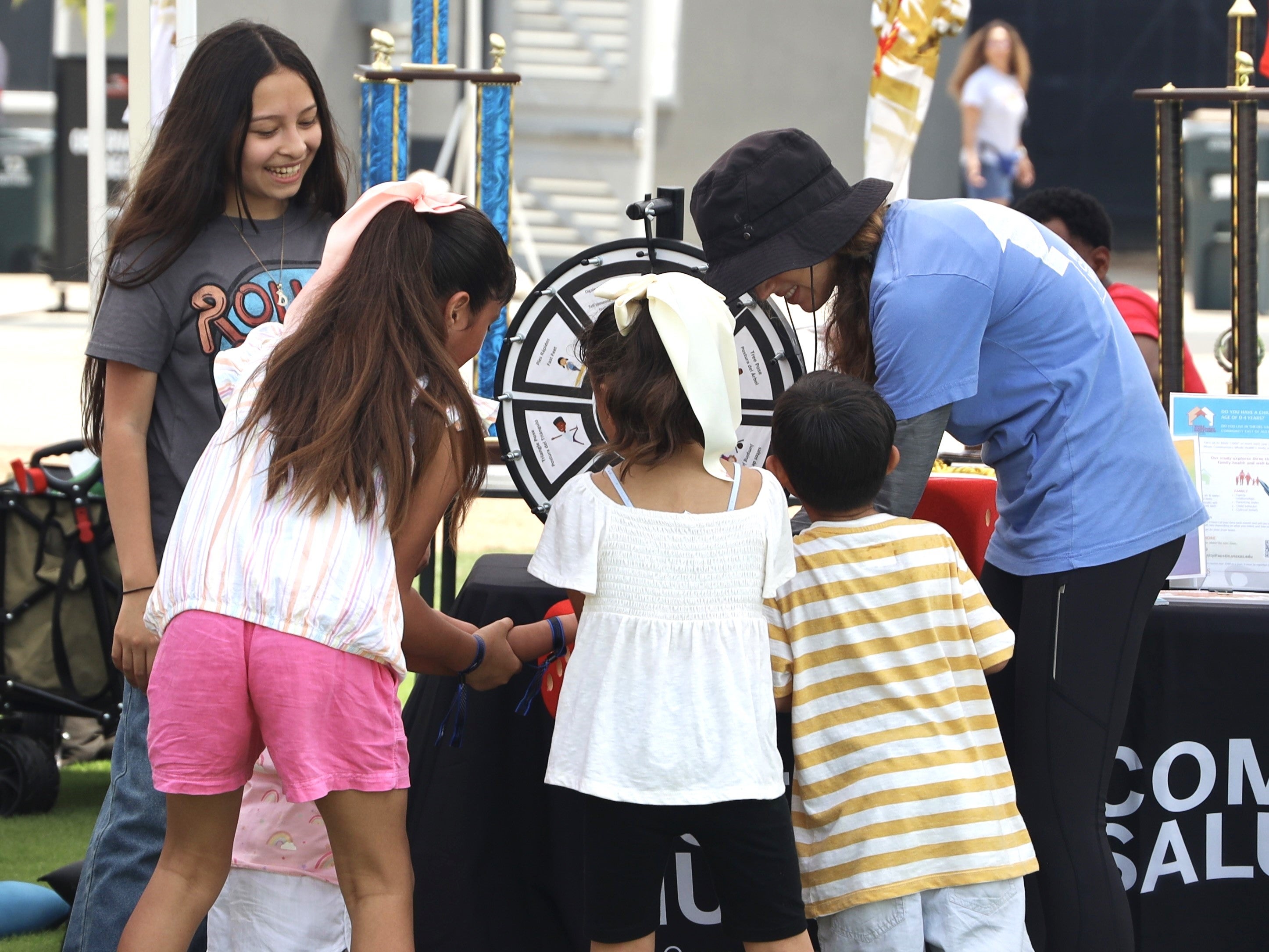Whole Communities–Whole Health Research Coordinator Sarah Smith (in hat), with children at Del Valle Day, June 2024.