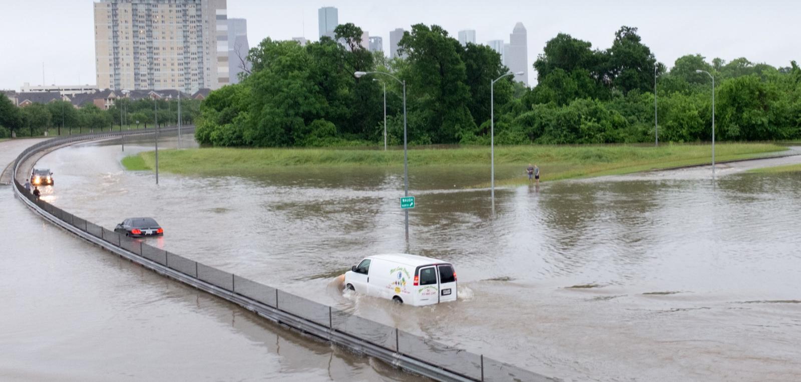 A van driving along a road in Houston, Texas is submerged in water during a flood event.