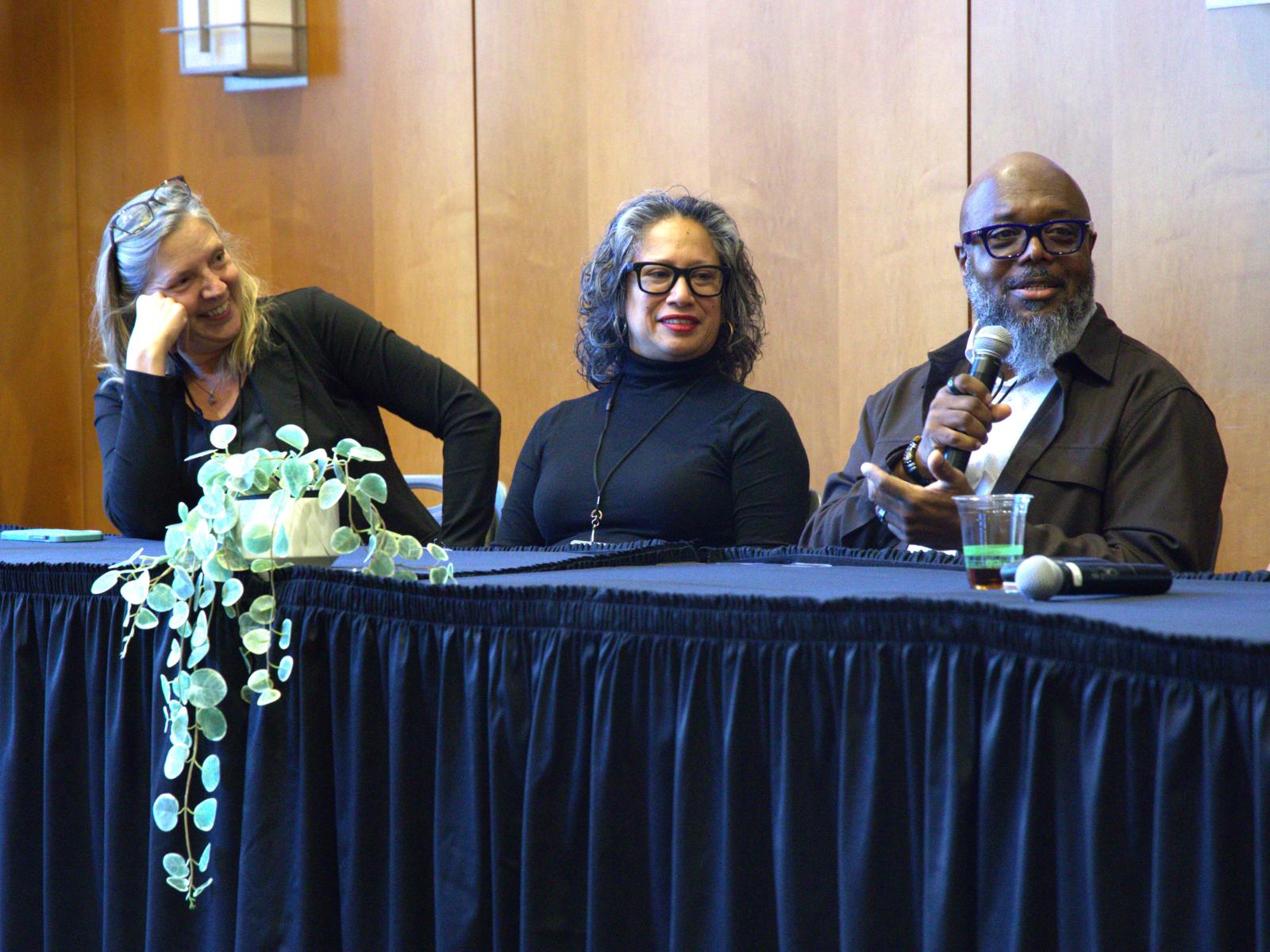 At the Whole Communities–Whole Health Symposium at UT Austin on February 6, 2026, Charles Moody, Jr. (right) speaks while Kerry Kinney (left) and Isela Guerra (middle) look on. Moody is smiling as he talks; Kinney is laughing.