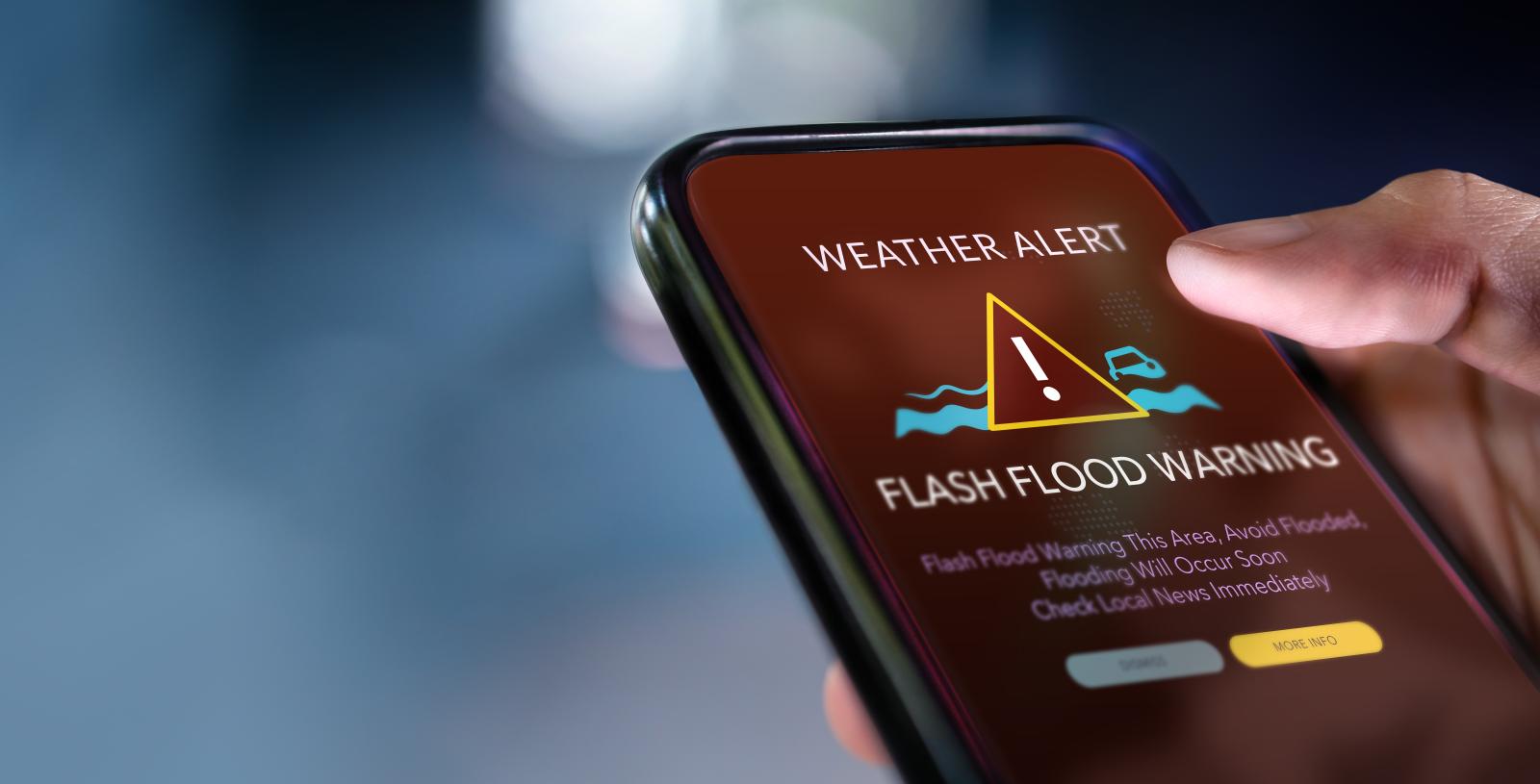 A flash flood warning alert displayed on a smartphone screen, indicating immediate danger