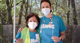 UT Nursing Associate Professor Karen Johnson is outside at a COVID-19 drive-through clinic in March 2021. She wears a face mask and holds a vaccine syringe and is standing next to a colleague also wearing a face mask.
