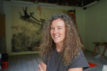 A casual photo of Marie Lorenz smiling. In the background is one of her exhibitions.